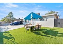 Backyard featuring a dining set with a blue umbrella on an artificial lawn at 5004 Cannon Blvd, Las Vegas, NV 89108