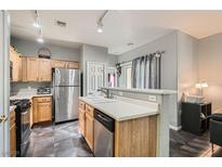 This kitchen features wood cabinetry, stainless steel appliances, and tiled flooring at 6321 Rolling Rose St # 201, North Las Vegas, NV 89081