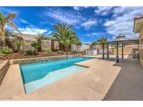 Inviting backyard oasis featuring a sparkling pool, mature palms, and a covered patio at 7427 Page Ranch Ct, Las Vegas, NV 89131