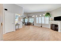 Bright living room features a fireplace, wood floors, and natural light from shuttered windows at 8450 Alta Dr # 204, Las Vegas, NV 89145