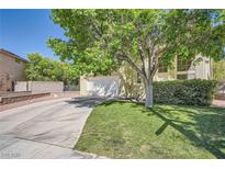 Well-maintained front yard featuring a green lawn, mature tree, and a spacious driveway leading to the garage at 1116 Avellino Ln, Las Vegas, NV 89144