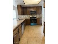 Kitchen featuring wooden cabinets, stainless steel appliances, and tile flooring at 5389 Spencer St, Las Vegas, NV 89119