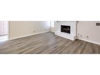 Bright living room with vinyl floors featuring a white painted brick fireplace at 3683 Villa Knolls East Dr, Las Vegas, NV 89120