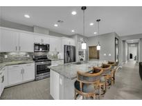 Modern kitchen with white cabinets, stainless steel appliances, granite counters and island with bar stool seating at 708 Kibbey St, Las Vegas, NV 89178