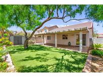 Lush backyard featuring a covered patio, storage shed, mature tree and manicured lawn at 8113 Danaides Ct, Las Vegas, NV 89131