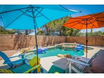 Backyard pool featuring rock details, colorful umbrellas, and lounge seating perfect for relaxation at 10902 Pentland Downs St, Las Vegas, NV 89141