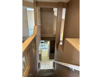View down the staircase toward the kitchen with tile floors and modern appliances, offering a glimpse into the home's layout at 1511 Balsam Mist Ave, Las Vegas, NV 89183