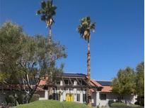 Charming desert home featuring solar panels, tile roof, and front yard palm trees at 1871 Ski Slope Cir, Las Vegas, NV 89117