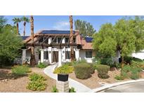 Charming single-story home featuring a landscaped front yard, pergola, desert landscaping, and solar panels on the roof at 1871 Ski Slope Cir, Las Vegas, NV 89117