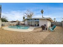 A refreshing pool is surrounded by a gravel backyard and a covered patio, perfect for outdoor enjoyment at 2496 Golfers St, Las Vegas, NV 89142