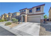 Two-story home featuring a beige exterior, rock accents, attached two-car garage, and well-maintained landscaping at 405 Prairie Moon Ave, North Las Vegas, NV 89084