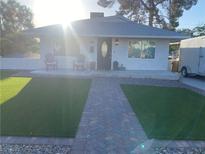 Charming single-story home with a manicured lawn and inviting front porch with chairs at 615 D Ave, Boulder City, NV 89005