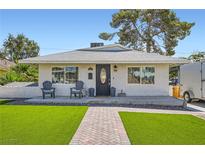 Charming single-story home with lush green lawn and inviting front porch with seating at 615 D Ave, Boulder City, NV 89005