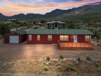 Charming home with a green roof, wooden deck, and detached garage, nestled against a mountain backdrop at 70 Camp Bonanza Rd, Las Vegas, NV 89124
