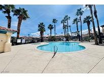 Community pool surrounded by well-manicured landscaping and palm trees on a sunny day at 8410 Eldora Ave # 2046, Las Vegas, NV 89117