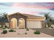 Charming single-story home featuring a stone facade, arched entryway, and a two-car garage, surrounded by desert landscaping at 135 Tropea Shore Dr, Henderson, NV 89011