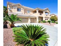 Inviting two-story home featuring a three-car garage, balcony, and beautifully landscaped front yard at 5808 Amber Station Ave, Las Vegas, NV 89131