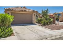 Charming single-story home featuring a two-car garage, desert landscaping, and a tile roof at 6446 Button Quail St, North Las Vegas, NV 89084