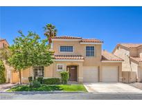 Charming two-story home with a well-manicured lawn, desert landscaping, and a classic tile roof under a clear blue sky at 2117 Desert Peak Rd, Las Vegas, NV 89134