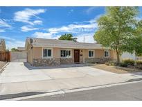 Charming single story home featuring a stone accent wall, lush landscaping, and a spacious driveway at 839 Benita Pl, Boulder City, NV 89005