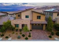 Contemporary two-story home featuring a brick driveway, desert landscaping, and mountain views at 12367 Aster Hills Ave, Las Vegas, NV 89138
