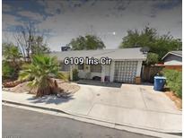 Charming single-story home with a spacious driveway, desert landscaping, and mature palm trees at 6109 Iris Cir, Las Vegas, NV 89107