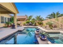 Inviting backyard pool featuring lush landscaping, a charming fire pit, and a serene outdoor living space at 6440 Bristlebird St, North Las Vegas, NV 89084