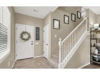 Bright entryway featuring a white door with wreath, neutral walls, and staircase leading to the upper level at 6869 Desert Thrasher Dr, North Las Vegas, NV 89084
