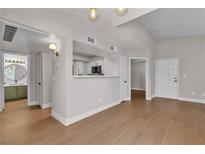 Bright and airy living room featuring modern lighting, wood floors, and views to the kitchen and bathroom at 1150 N Buffalo Dr # 2025, Las Vegas, NV 89128
