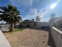 View of the gravel-filled backyard with a palm tree and a block wall at 1429 S Sandhill Rd, Las Vegas, NV 89104