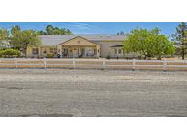 Charming single-story home with a white fence, gravel driveway, and mature trees providing shade and curb appeal at 3231 Rebel Ave, Pahrump, NV 89048