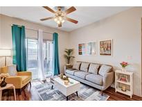 Bright living room with a ceiling fan, a plush gray sofa, and sliding glass doors to a balcony at 5751 E Hacienda Ave # 154, Las Vegas, NV 89122