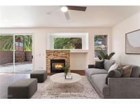 Comfortable living room featuring a stone fireplace, ceiling fan, and sliding doors to the backyard at 10505 Jeremy Ridge Ave, Las Vegas, NV 89144