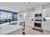Bright kitchen features white cabinetry, stainless steel appliances, and a modern marble countertop island with dining area at 217 Turkey Creek Way, Henderson, NV 89074