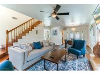 Inviting living room with staircase, wood floors, ceiling fan, and view to the dining area at 2829 Via Florentine St, Henderson, NV 89074