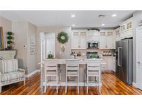 Bright kitchen features white cabinets, stainless appliances, island with breakfast bar and wood floors at 3185 Mura Del Prato Ave, Henderson, NV 89044
