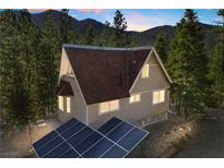 Charming A-frame home with a brown roof, solar panels, and nestled among tall trees against a mountain backdrop at 5230 Whispering Robin Ln, Mount Charleston, NV 89124