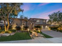 Beautiful two-story home with stone accents, manicured landscaping, and illuminated walkway leading to the front entrance at 9 Clear Crossing Trl, Henderson, NV 89052