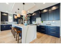 A modern kitchen featuring navy blue cabinets, a large island, pendant lighting, and stainless steel appliances at 2750 Evolutionary Ln, Las Vegas, NV 89138