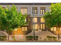 Inviting multi-level home featuring a blend of neutral tones, brick accents, and lush landscaping at 3159 Via Como, Henderson, NV 89044