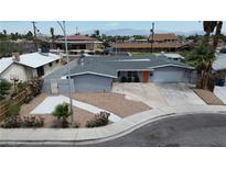 Charming single-story home with an orange door, grey exterior paint, desert landscaping and a long driveway at 4404 Hillcrest Ave, Las Vegas, NV 89102