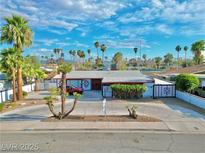 Charming single-story home with mature landscaping and a circular driveway, under a bright blue sky at 1589 Silver Mesa Way, Las Vegas, NV 89169