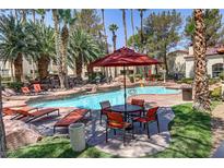 Inviting community pool featuring lounge chairs, tables, mature landscaping, and a rock waterfall feature at 2975 Bluegrass Ln # 811, Henderson, NV 89074