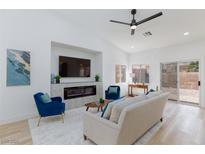Bright living room with fireplace, modern ceiling fan, and sliding glass door access at 4176 Demoline Cir, Las Vegas, NV 89141