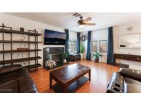 Inviting living room with a cozy fireplace, modern TV, wood-look floors and bright windows at 944 Angel Star Ln, Las Vegas, NV 89145
