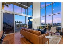 Modern living room featuring high ceilings, floor-to-ceiling windows, and a sliding glass door to the outdoor patio at 11441 Allerton Park Dr # 212, Las Vegas, NV 89135
