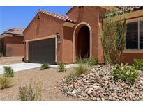 Charming single-story home featuring a two-car garage, arched entryway, and desert landscaping at 1398 Pin Cushion Rdg, Mesquite, NV 89034