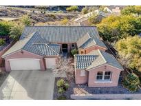 Aerial view of a pink stucco home with a tile roof, three-car garage, and desert landscaping at 2039 Colvin Run Dr, Henderson, NV 89052