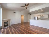 Bright living room with fireplace, ceiling fan and wood floors open to kitchen with stainless steel appliances at 4960 Harrison Dr # 214, Las Vegas, NV 89120