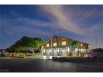 Charming two-story home with three-car garage, lush tree, and illuminated façade at twilight at 7761 Cowboy Trl, Las Vegas, NV 89131